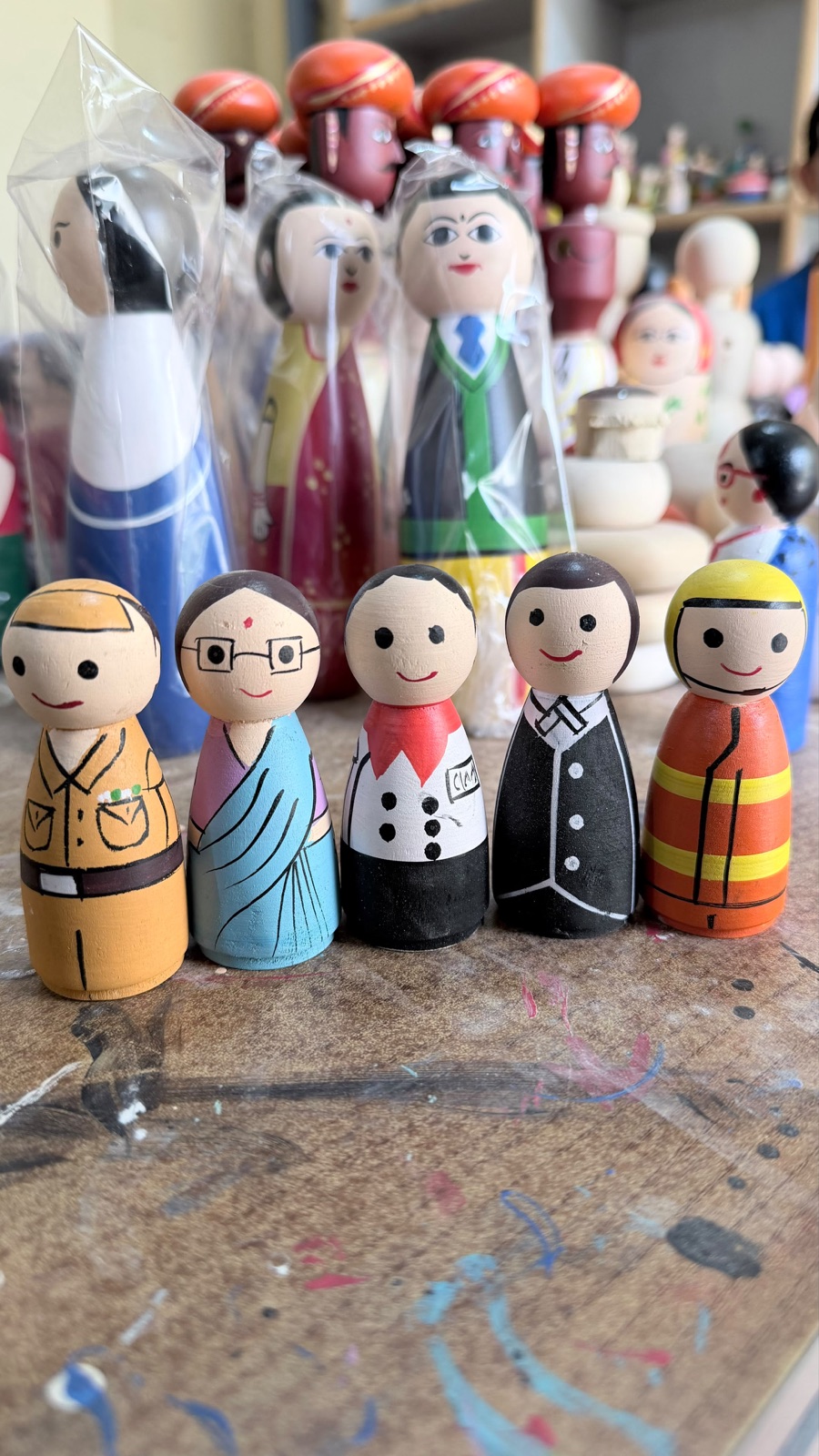 Hand-painted wooden community figures arranged on a working table