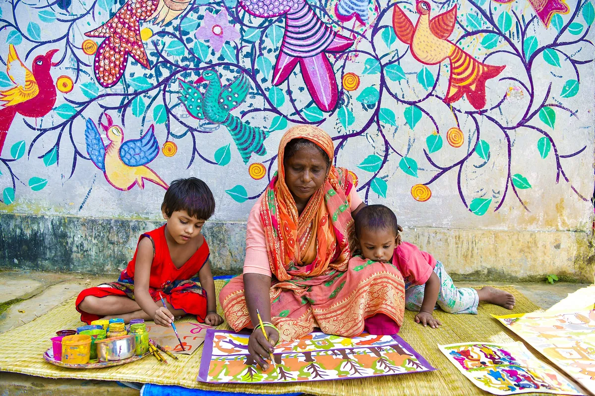 A Bengal Patachitra artist painting with children