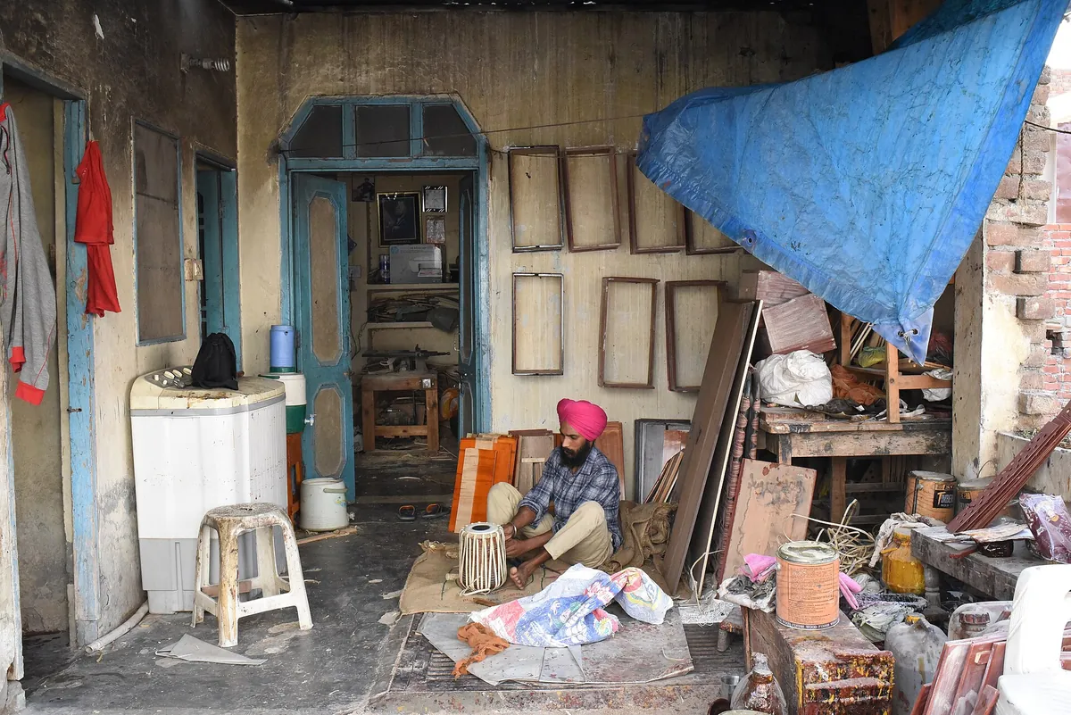 A tabla maker working by hand in a small instrument workshop