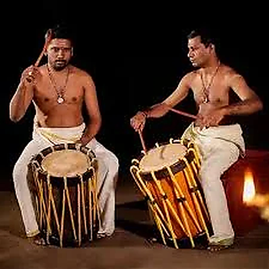 Two Kerala musicians playing the Chenda, showing the cylindrical shell, hide heads and rope lacing